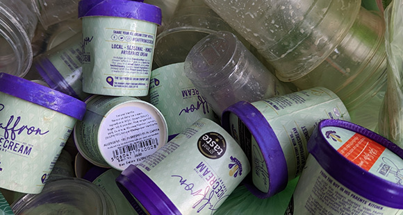 a number of different branded ice cream tubs in a recycling bin