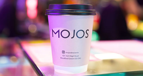 a coffee cup branded Mojos on a glass table